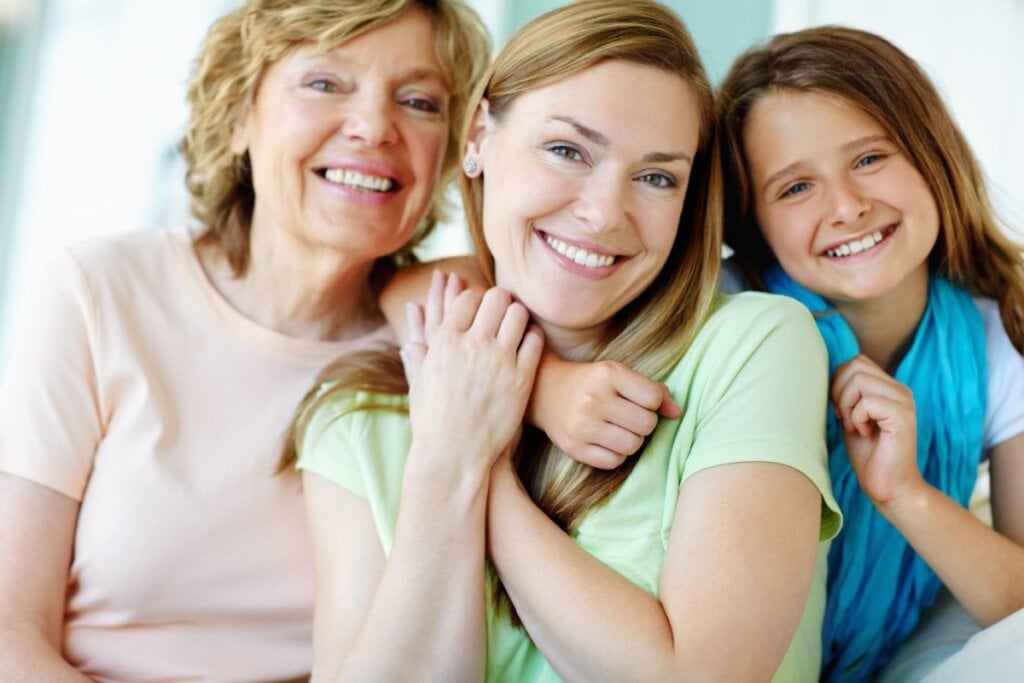 Mulher sendo abraçada pela mãe e pela filha