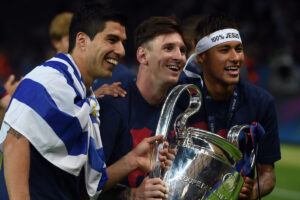 Neymar ao lado de Suárez e Messi, com os três segurando a taça da Champions League (foto: AFP PHOTO / PATRIK STOLLARZ)