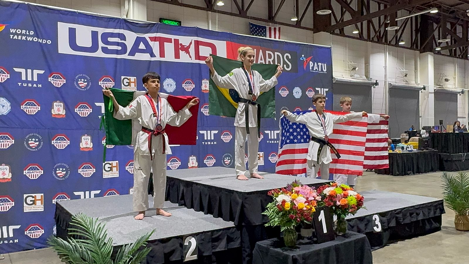 Theo Cadena com a bandeira brasileira no pódio do US Open de Taekwondo 2025 (foto: Evelyn Cris/Divulgação)